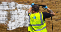 Graffiti being removed from wall with pressure washing
