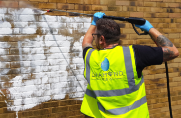 Graffiti being removed from wall with pressure washing